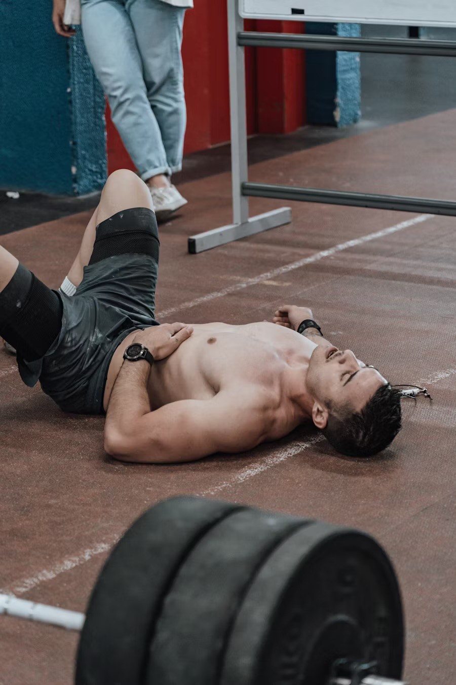 A man lying on the gym floor recovering after a training set