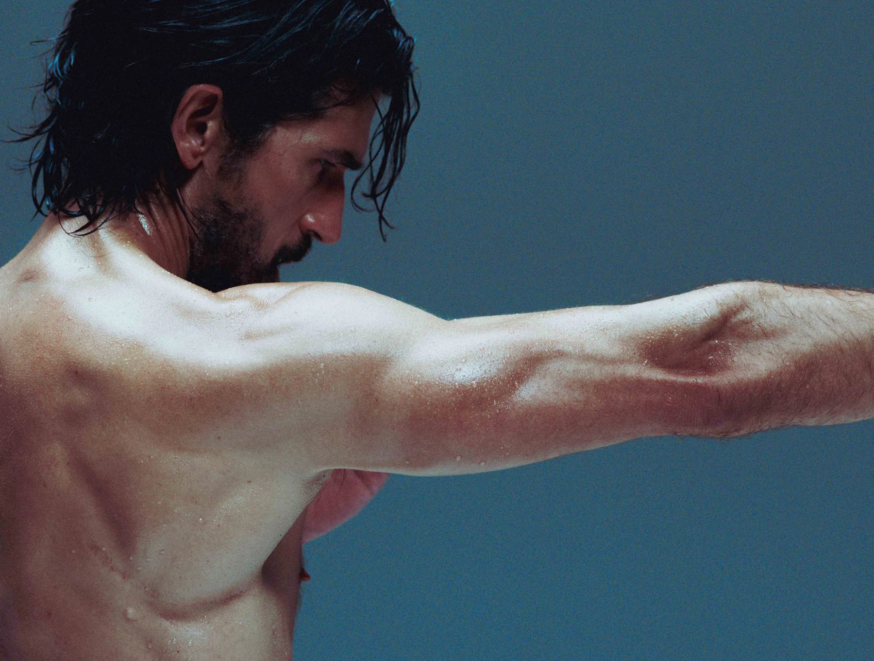 Close view of a man's shoulder and back as he extends his arm