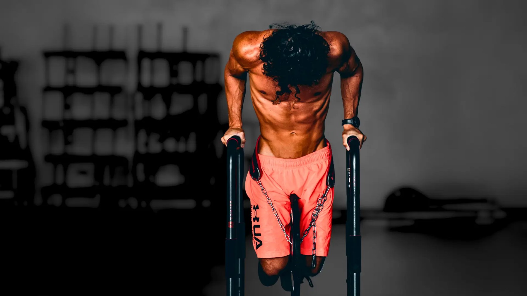 A man performing controlled dips on parallel bars in a gym
